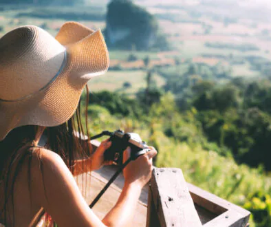 Summer beautiful girl holding a mountain view camera
